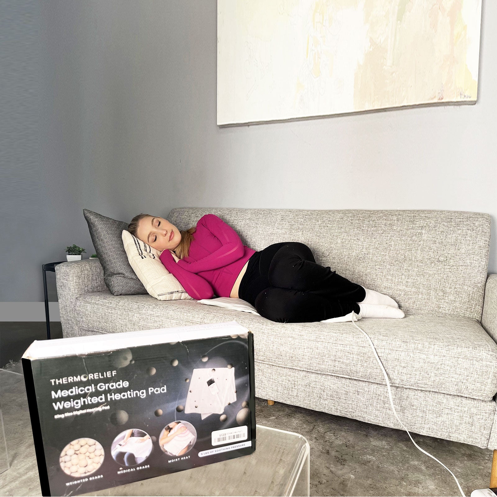 Person lying on a couch with a weighted heating pad box in the foreground